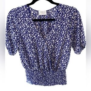 Faux wrap top with a snap closure & smocked at the  waist.